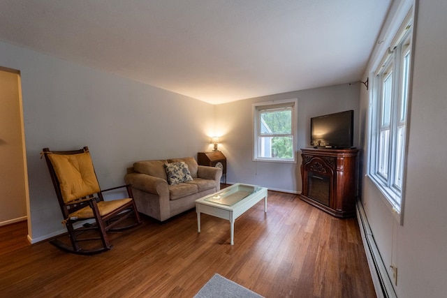 living area featuring wood finished floors, a baseboard radiator, and baseboards