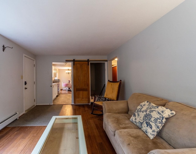 living area featuring wood finished floors, a barn door, baseboard heating, and baseboards