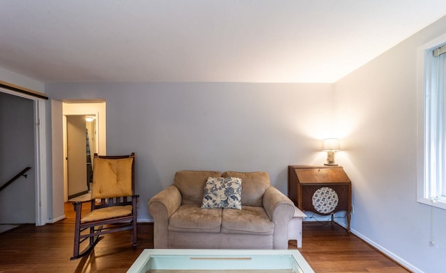 living area with wood finished floors, baseboards, and an upstairs landing