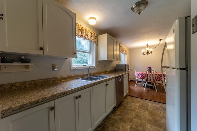 kitchen with appliances with stainless steel finishes, a sink, a chandelier, white cabinets, and baseboard heating