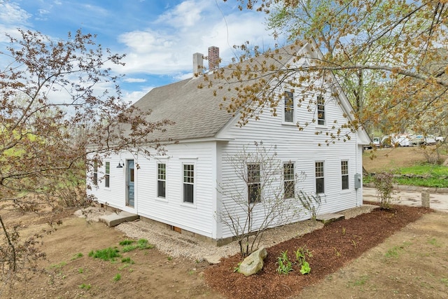 view of property exterior with a chimney and roof with shingles