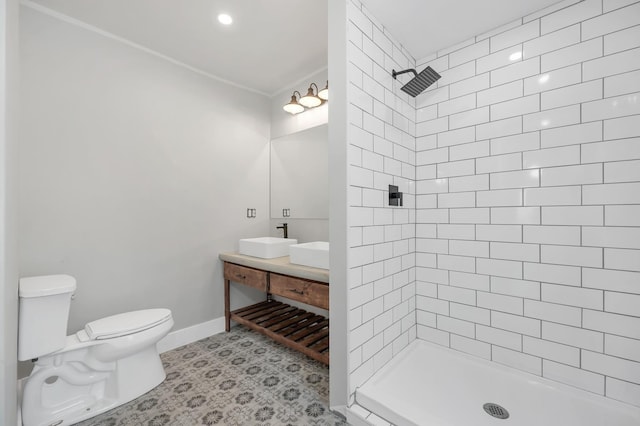 full bathroom featuring toilet, a tile shower, double vanity, ornamental molding, and baseboards