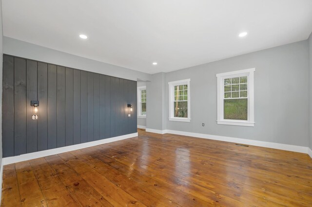 spare room with hardwood / wood-style flooring, baseboards, recessed lighting, and wooden walls