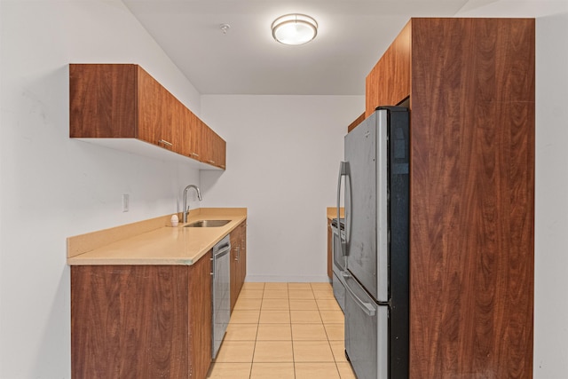 193 St Paul St Unit 101, Burlington, VT 05401 - kitchen with a sink, appliances with stainless steel finishes, brown cabinetry, light countertops, and light tile patterned flooring