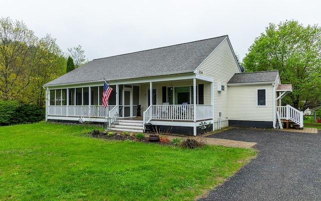 view of front facade featuring covered porch, roof with shingles, a front yard, and driveway