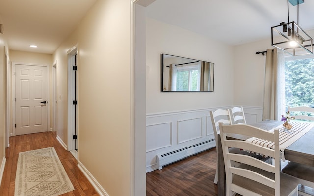 dining area featuring a baseboard radiator, wood finished floors, wainscoting, and recessed lighting