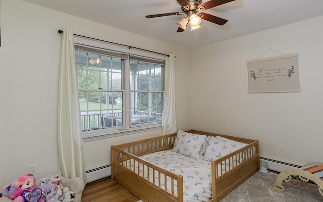 bedroom with baseboard heating, a ceiling fan, and wood finished floors