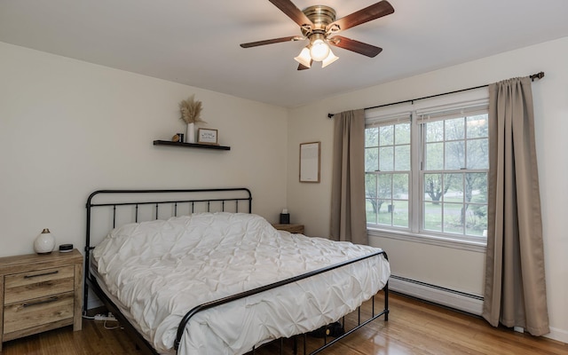 bedroom featuring a baseboard radiator, wood finished floors, and a ceiling fan
