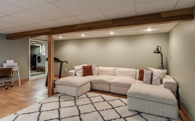 living room featuring separate washer and dryer, light wood-style flooring, baseboards, a drop ceiling, and recessed lighting