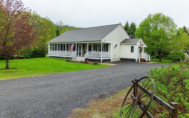 view of front of home with covered porch, a shingled roof, a front yard, and driveway