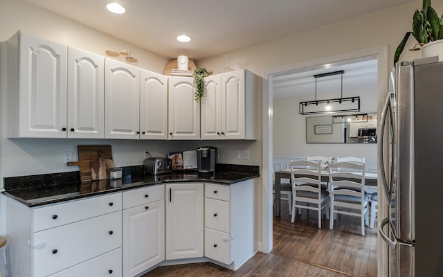 kitchen with freestanding refrigerator, white cabinetry, wood finished floors, dark stone countertops, and recessed lighting