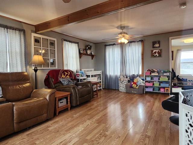 living area with a ceiling fan, wood finished floors, beamed ceiling, and crown molding
