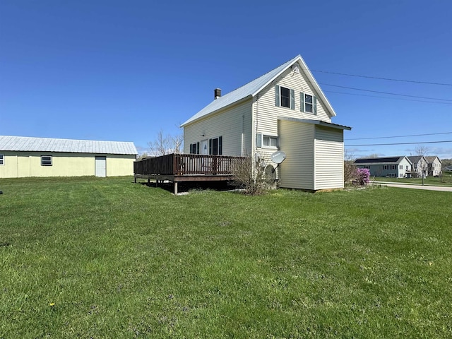 rear view of property with a wooden deck, a yard, and metal roof