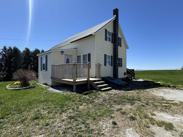 view of property exterior with a chimney, a wooden deck, a lawn, and metal roof