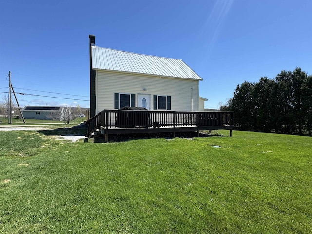 rear view of property with a deck, a yard, metal roof, and a chimney