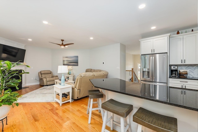 11 Carriage Hill Rd, Wilton, NH 03086 - kitchen with stainless steel fridge, light wood finished floors, decorative backsplash, a breakfast bar area, and a ceiling fan
