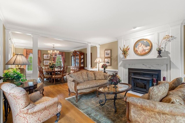 12 Mcintosh Ln, Bedford, NH 03110 - living room with decorative columns, ornamental molding, a fireplace with flush hearth, light wood finished floors, and a chandelier