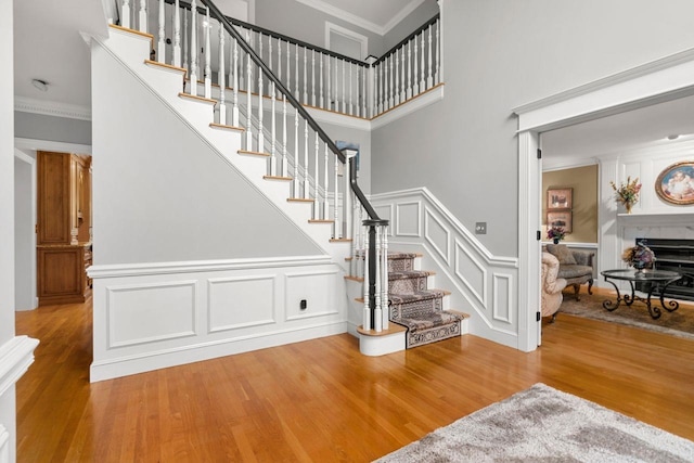 12 Mcintosh Ln, Bedford, NH 03110 - stairway with wood finished floors, crown molding, a fireplace, a decorative wall, and wainscoting