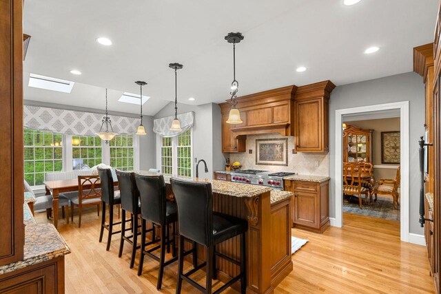 12 Mcintosh Ln, Bedford, NH 03110 - kitchen with brown cabinetry, light wood finished floors, light stone counters, pendant lighting, and recessed lighting