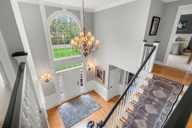 12 Mcintosh Ln, Bedford, NH 03110 - entrance foyer featuring a chandelier, light wood-style floors, crown molding, stairs, and a wainscoted wall