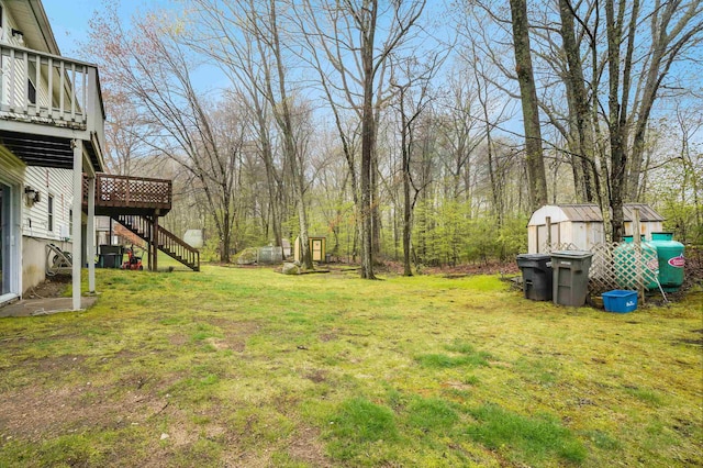 view of green lawn with a storage shed, stairway, an outbuilding, and a deck
