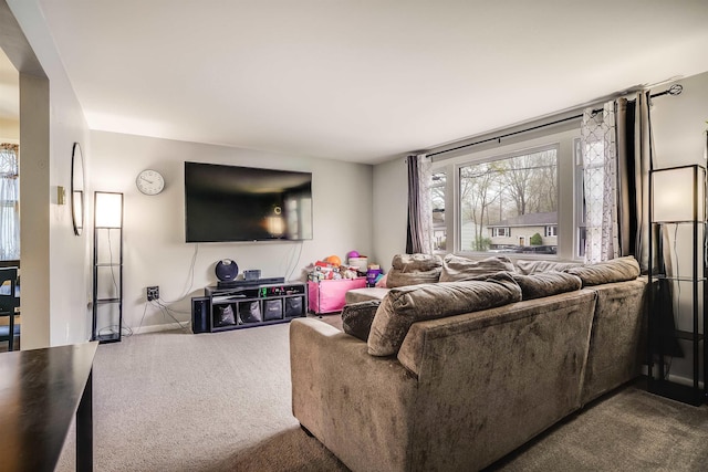 living area featuring dark carpet, plenty of natural light, and baseboards