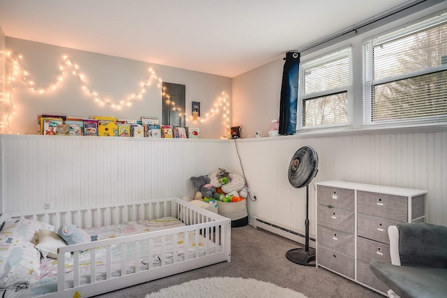bedroom with a wainscoted wall, baseboard heating, carpet floors, and a crib