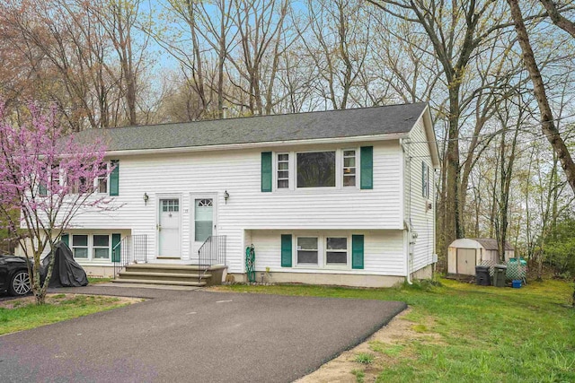 bi-level home featuring a storage unit, an outbuilding, and a front yard