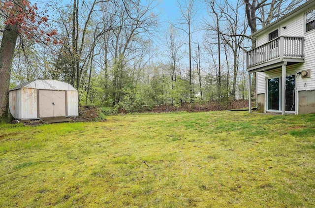 view of grassy yard with a storage unit, a balcony, and an outdoor structure