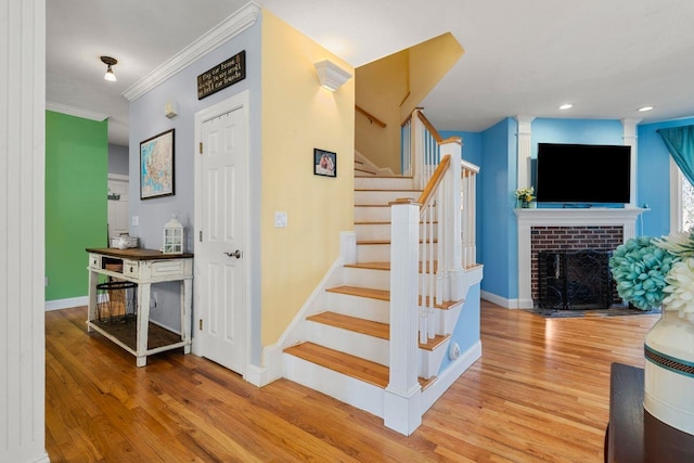 38 Farmington Rd, Nashua, NH 03060 - stairway featuring wood finished floors, baseboards, ornamental molding, a brick fireplace, and recessed lighting