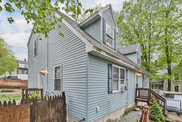 view of side of property with fence and a shingled roof