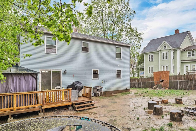 rear view of property featuring fence, a deck, and a gazebo
