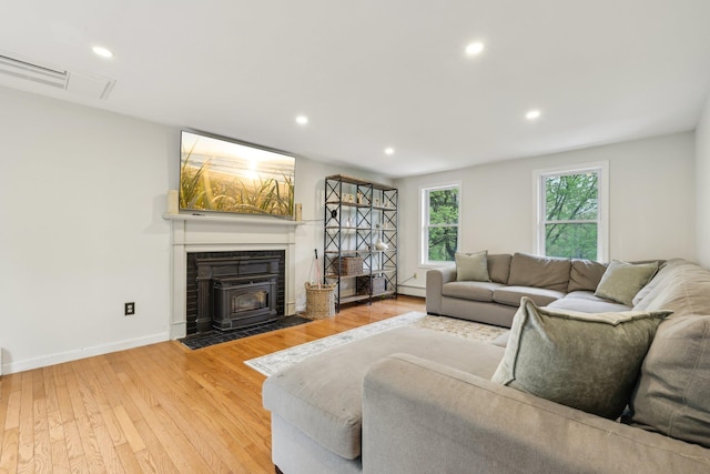 living room with a wood stove, light wood-style flooring, recessed lighting, and baseboards