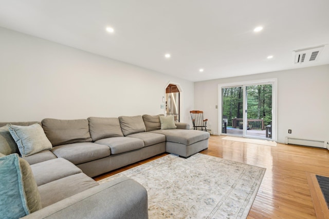 living room featuring arched walkways, a baseboard radiator, recessed lighting, and light wood-style flooring
