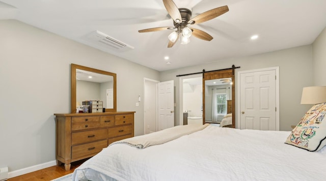 bedroom with recessed lighting, light wood finished floors, baseboards, a barn door, and a baseboard radiator