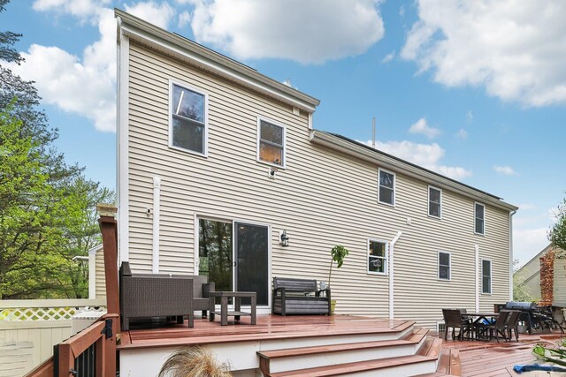 rear view of property featuring outdoor dining area and a wooden deck