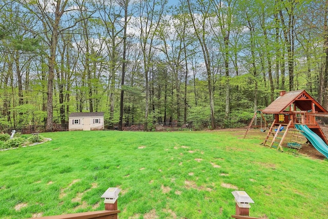 view of grassy yard featuring a playground, a shed, and an outbuilding