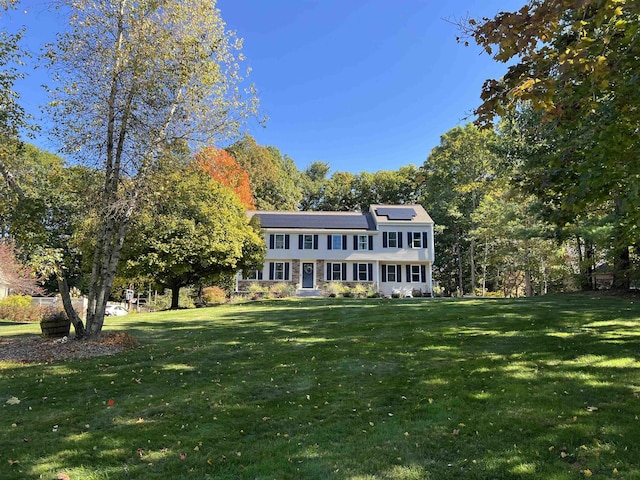 view of front of home featuring solar panels and a front lawn
