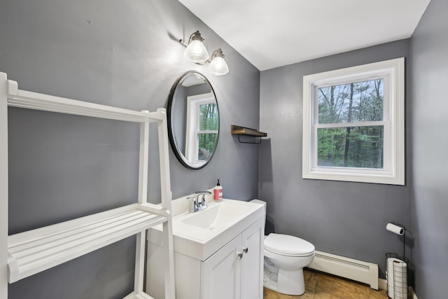 bathroom featuring baseboard heating, healthy amount of natural light, toilet, and vanity