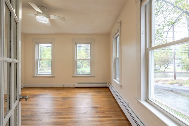 empty room with a baseboard heating unit, a ceiling fan, and light wood-style floors