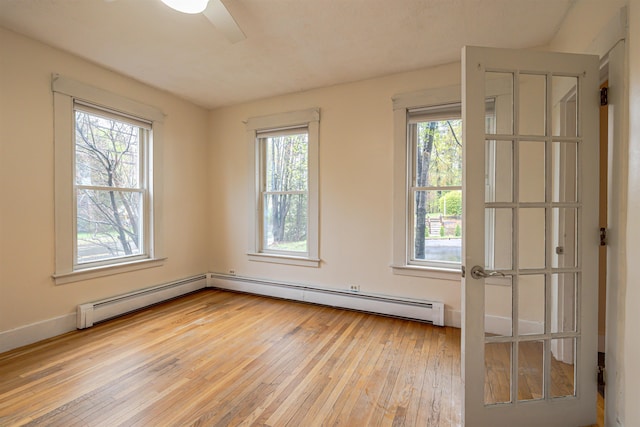spare room featuring hardwood / wood-style flooring, healthy amount of natural light, ceiling fan, and a baseboard heating unit