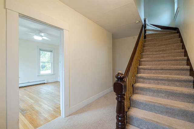 stairs featuring baseboard heating, wood finished floors, baseboards, and ceiling fan