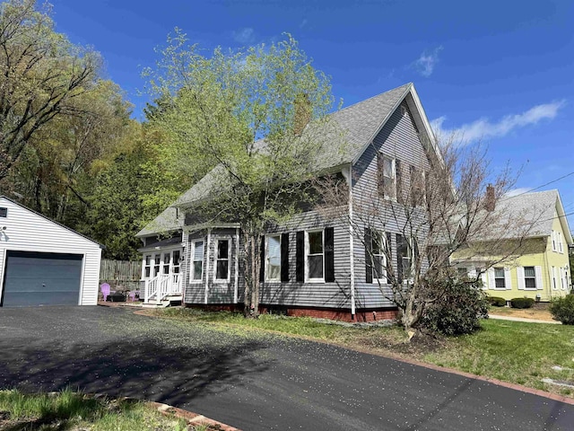 view of front facade featuring an outdoor structure, a chimney, and a garage