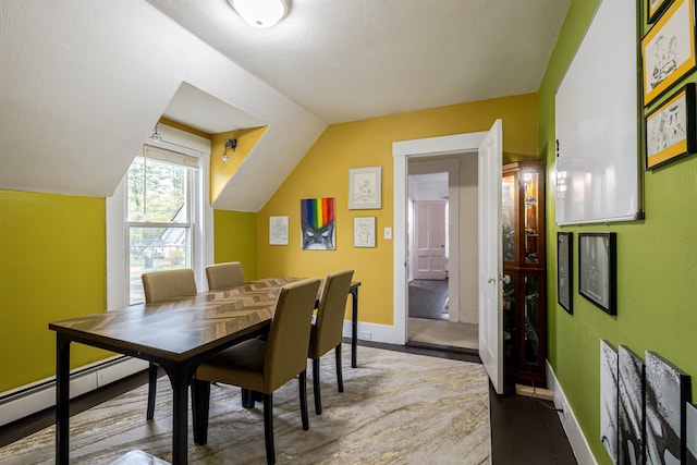 dining space with baseboards, baseboard heating, vaulted ceiling, and light wood-style flooring