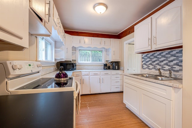 kitchen with white range with electric stovetop, black microwave, a sink, white cabinets, and light wood finished floors