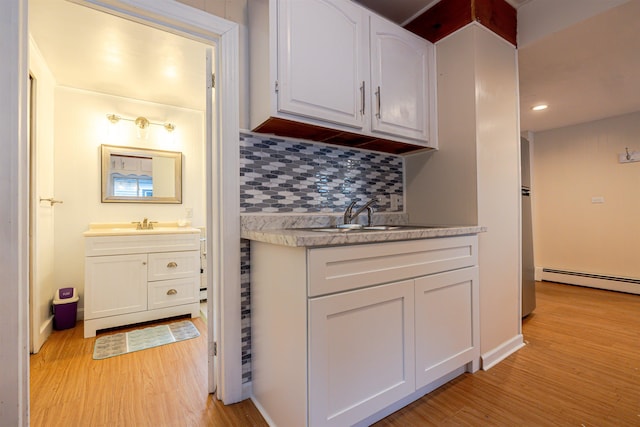 kitchen featuring a baseboard radiator, light wood-type flooring, decorative backsplash, white cabinets, and light countertops