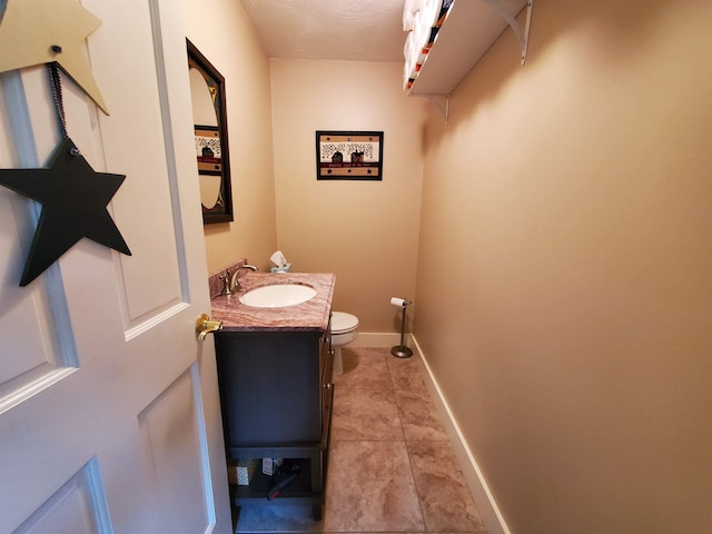 bathroom with toilet, vanity, tile patterned floors, and baseboards