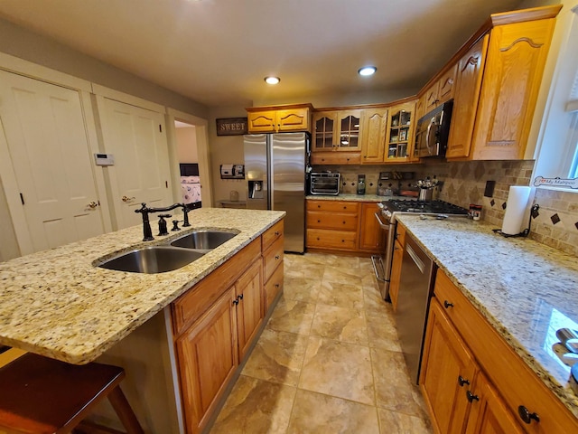 kitchen with a sink, appliances with stainless steel finishes, brown cabinetry, backsplash, and recessed lighting