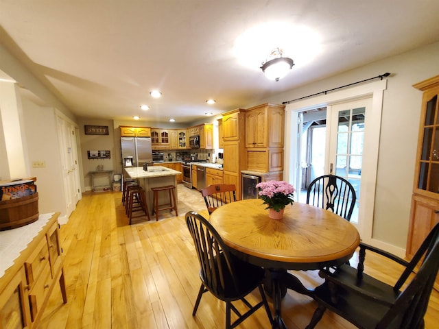 dining room featuring wine cooler, light wood-style flooring, recessed lighting, baseboards, and french doors
