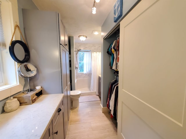 bathroom with a shower stall, toilet, and wood finished floors